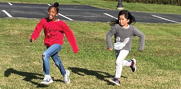 two girls running in field